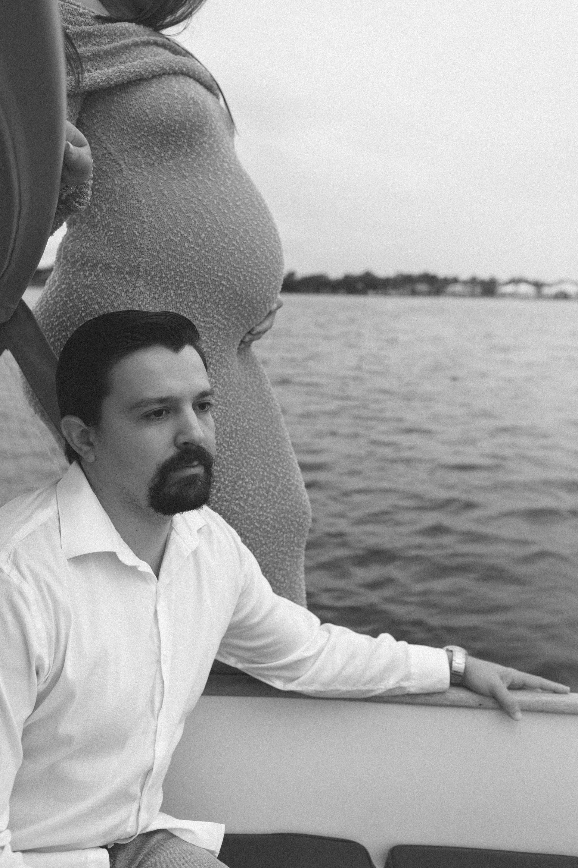 A man is sitting on a boat next to a pregnant woman