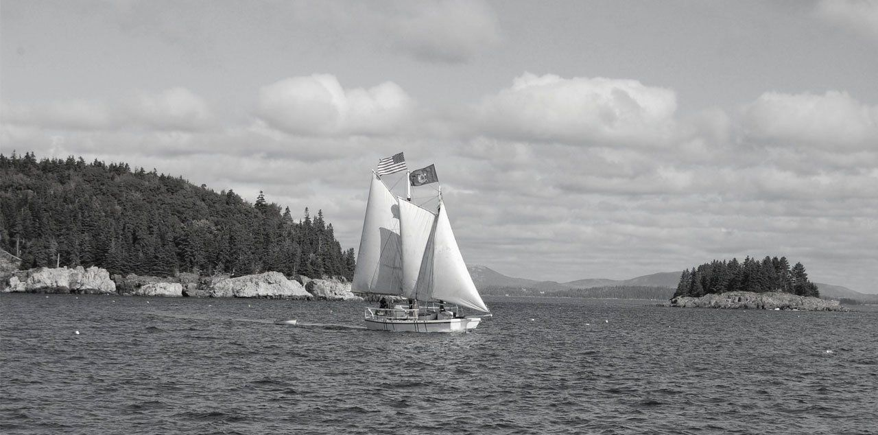 A black and white photo of a sailboat in the ocean.  Schooner Lily sailing in Maine before she came to Stuart, Florida