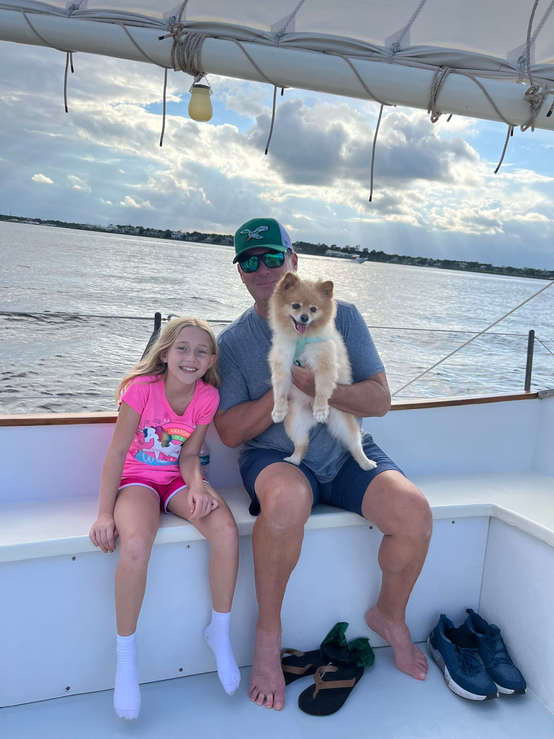 A man and a little girl are sitting on a boat holding a dog.