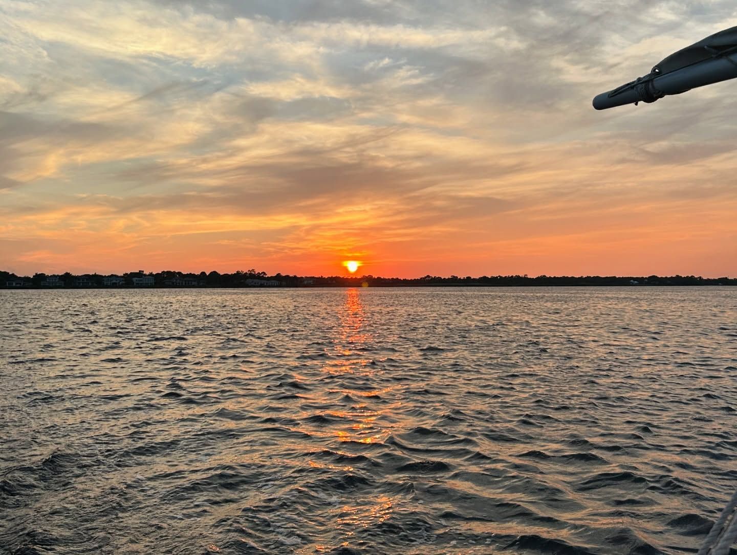 Sunset over rippling water; orange and yellow sky; sun reflecting on waves.