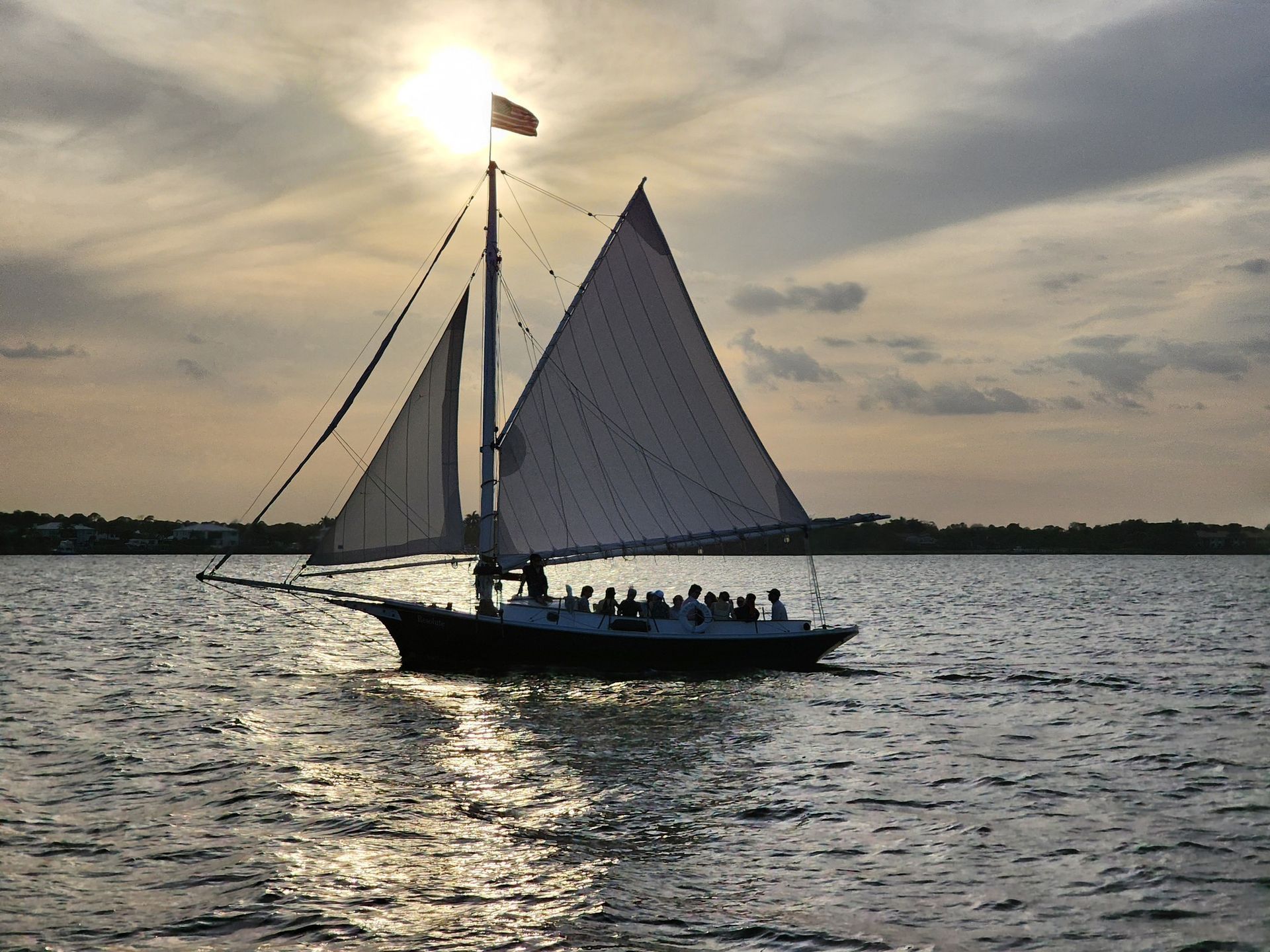 A sailboat with the sun shining through the sails