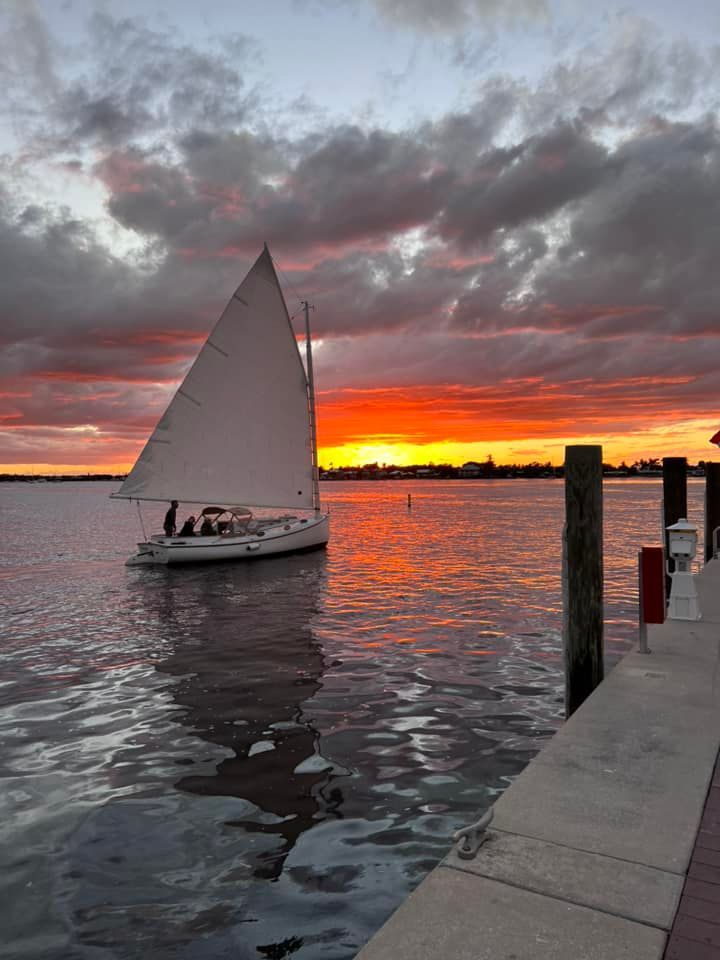 A sailboat is docked at a dock at sunset.