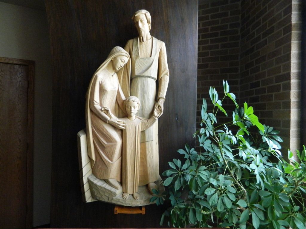 Wooden relief sculpture of a family group, with two adults and a child.