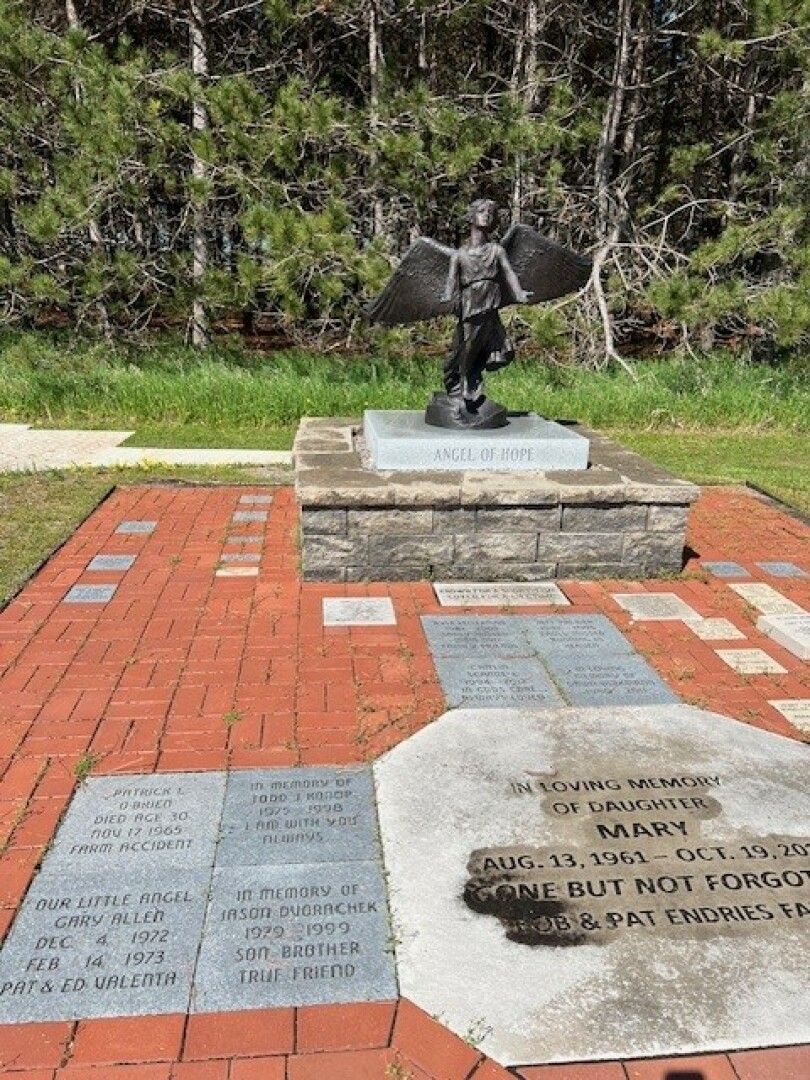 A bronze angel statue titled Angel of Hope stands on a stone pedestal.