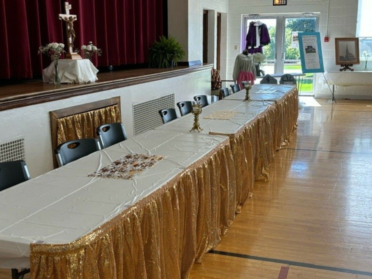 Long table with gold skirt and white tablecloth set in a hall.