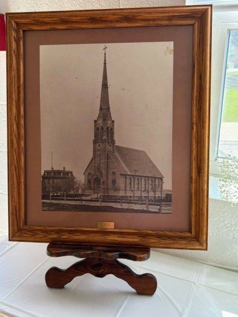 Framed sepia-toned photo of a historic church with a tall steeple, displayed on a wooden stand.