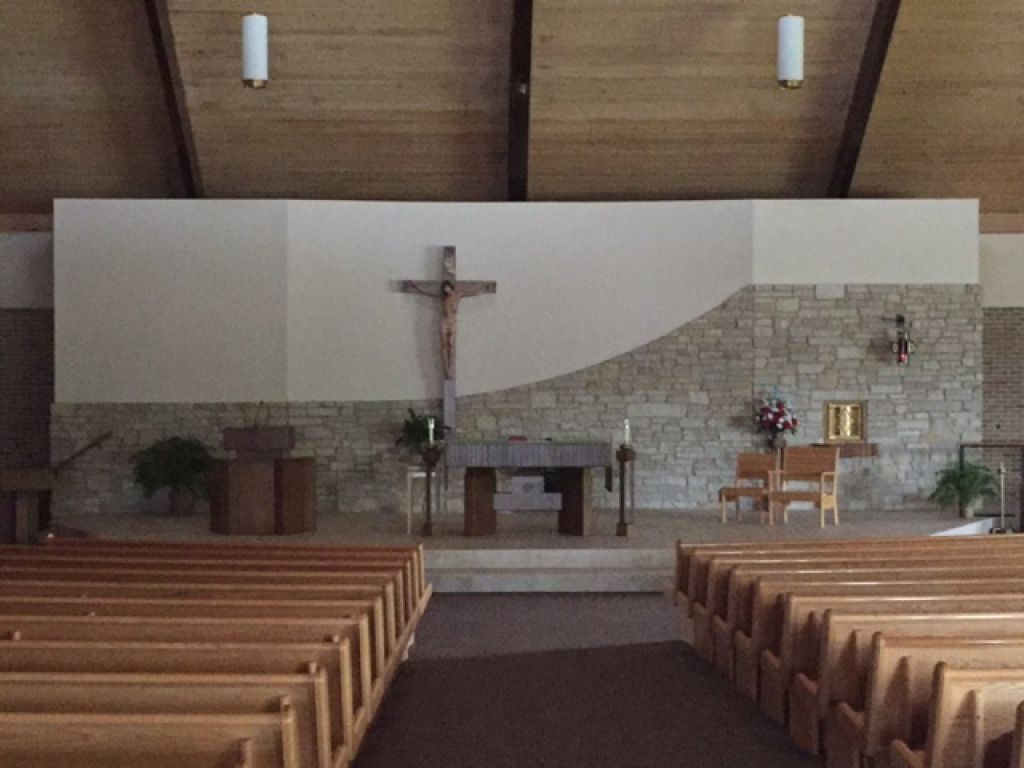 Church interior with wooden pews facing a stone altar.