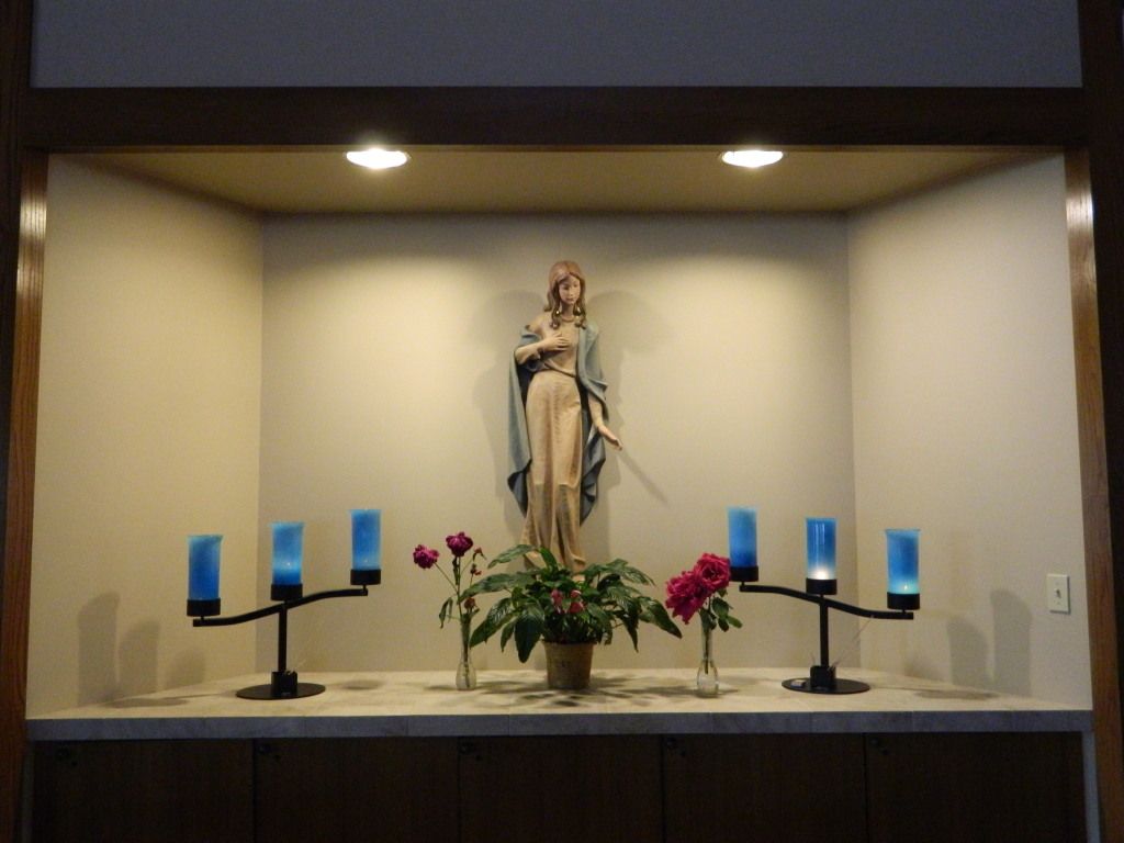 Statue of a robed figure in a small alcove, surrounded by blue candles.