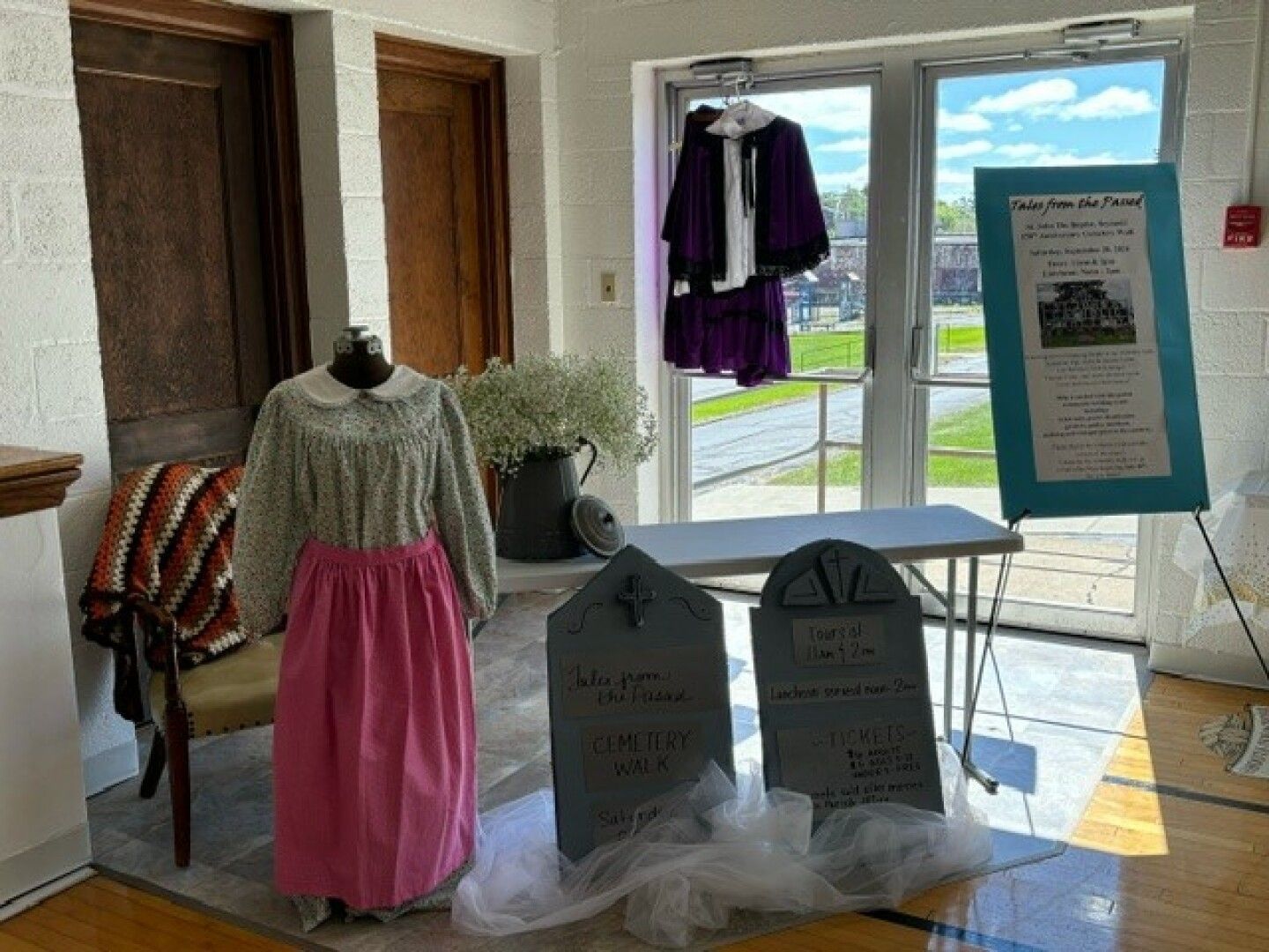 Decorative tombstones with painted text advertise a cemetery walk. 