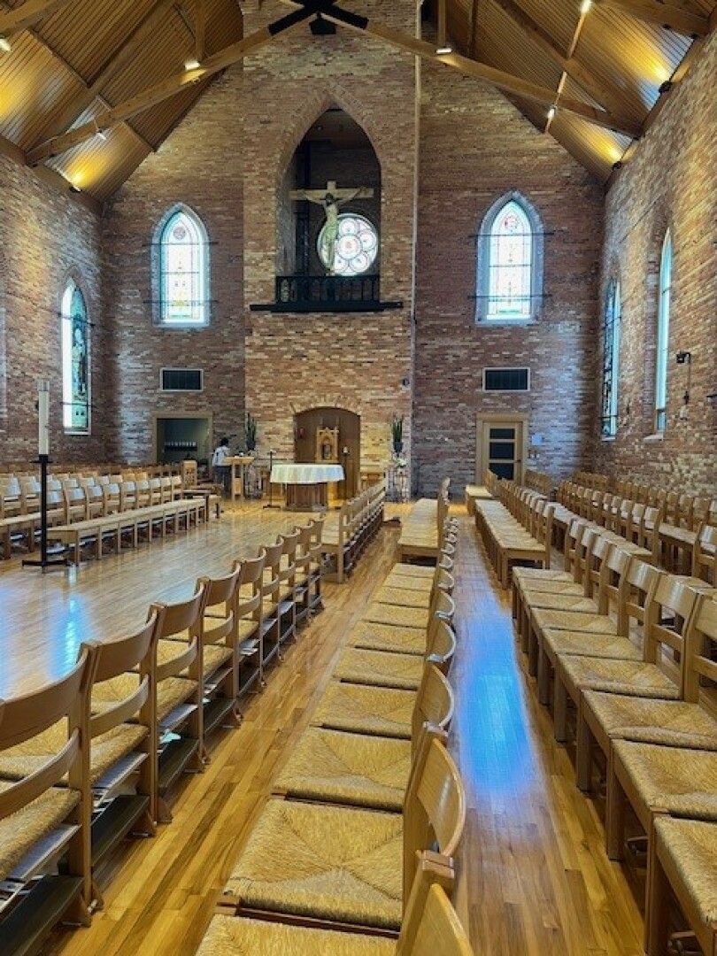 Interior of a brick church with wooden pews lining the aisle.
