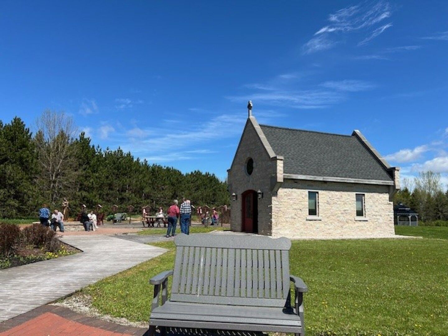 A small stone building with a red door stands under a clear blue sky. 