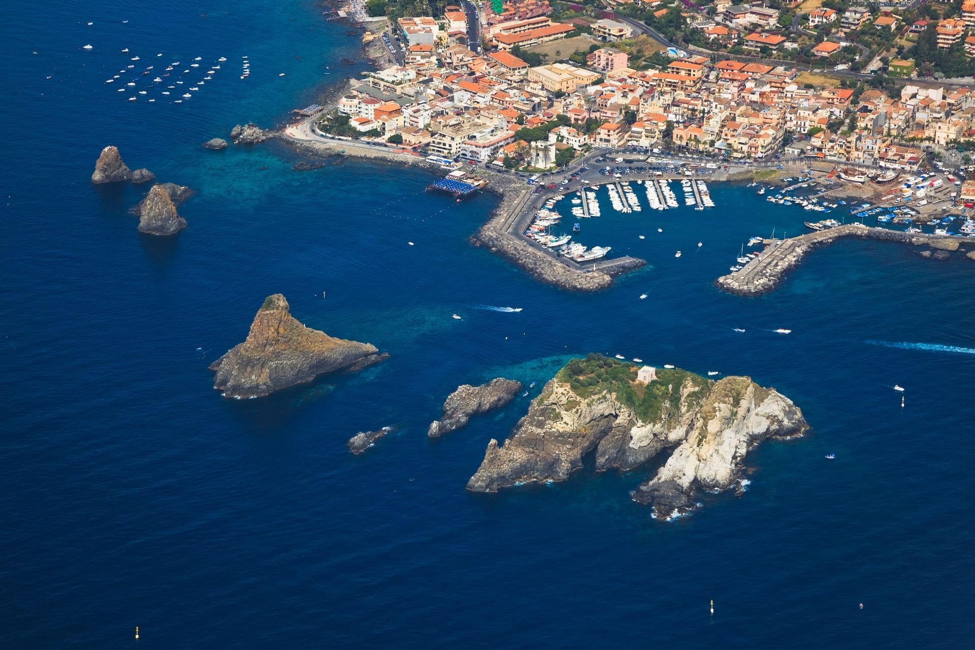 Aerial view of the Cyclops Islands off Sicily, Italy, with clear blue water and harbor town.