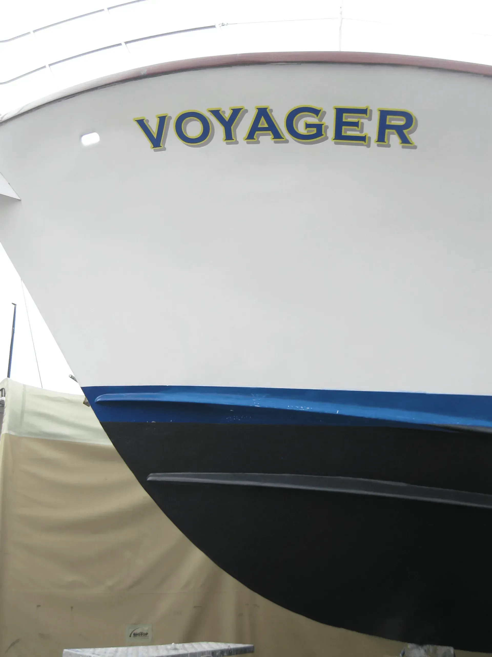 White boat bow with VOYAGER in green letters; blue stripe above black hull.