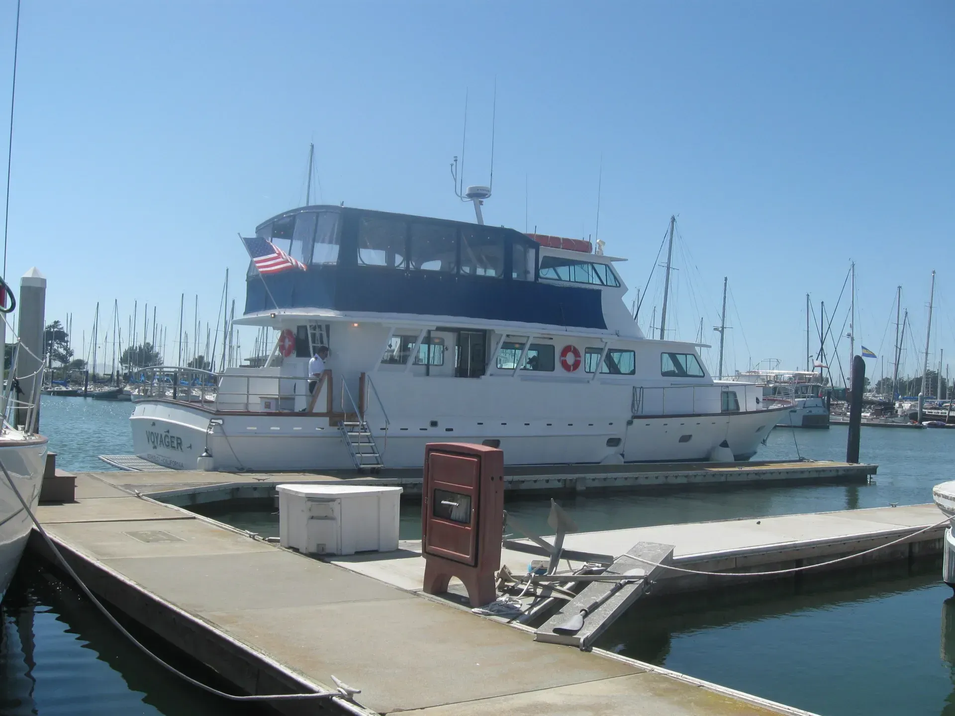 White boat with blue trim docked at a marina on a sunny day.