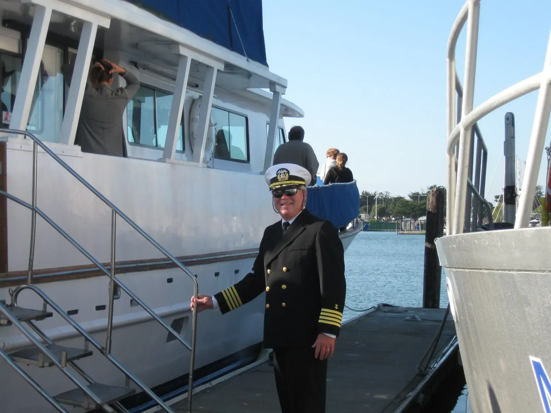 Sunset over a lake surrounded by green hills, with a grassy foreground and cloudy sky.