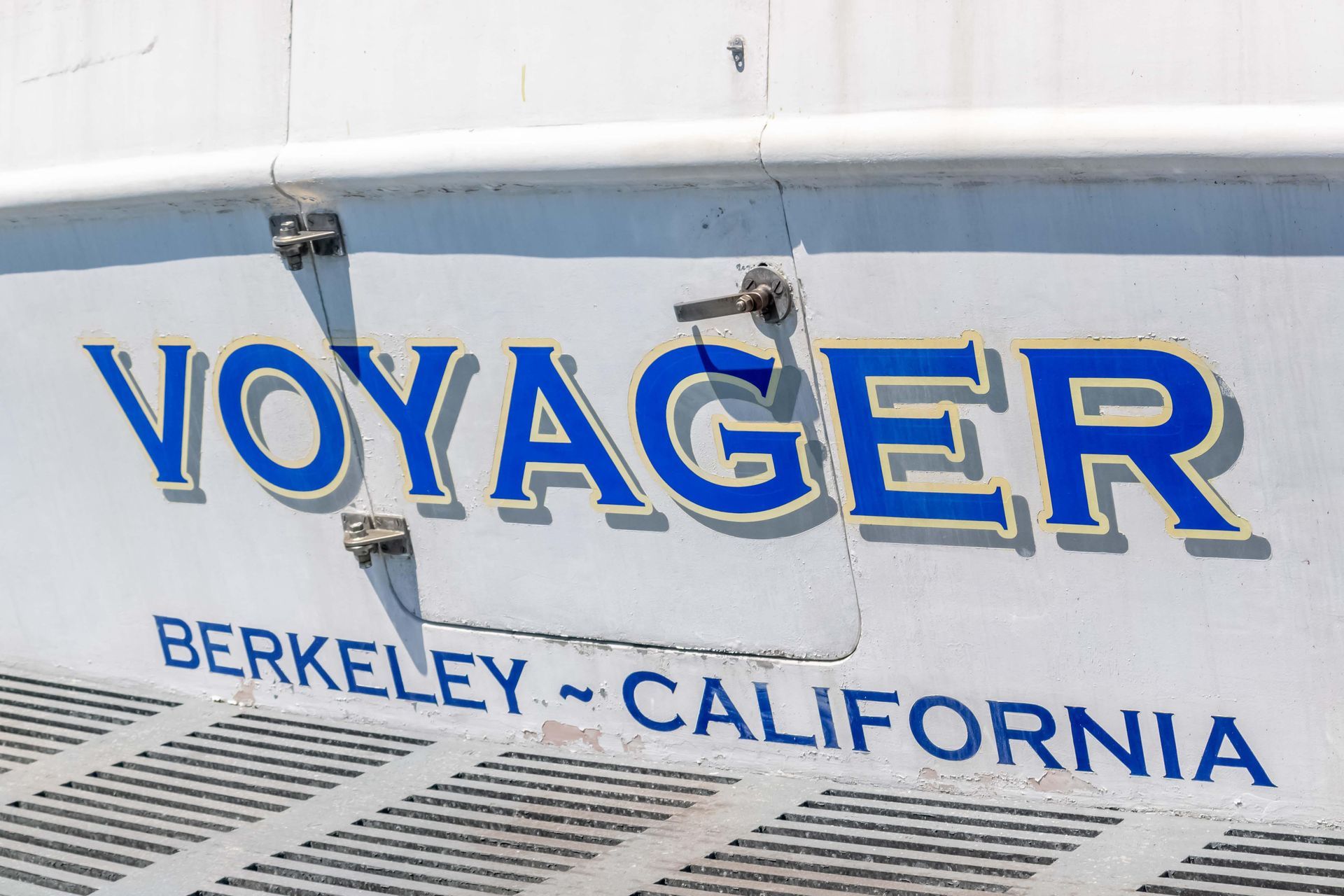 Person walking on a sandy beach, waves crashing, rocks and cliffs in the background.