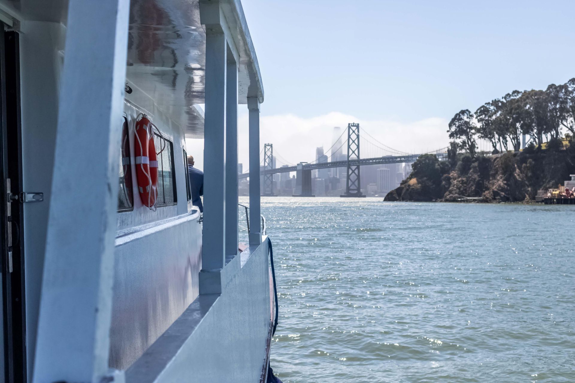 Woman embraces another, holding an urn and book at the beach.