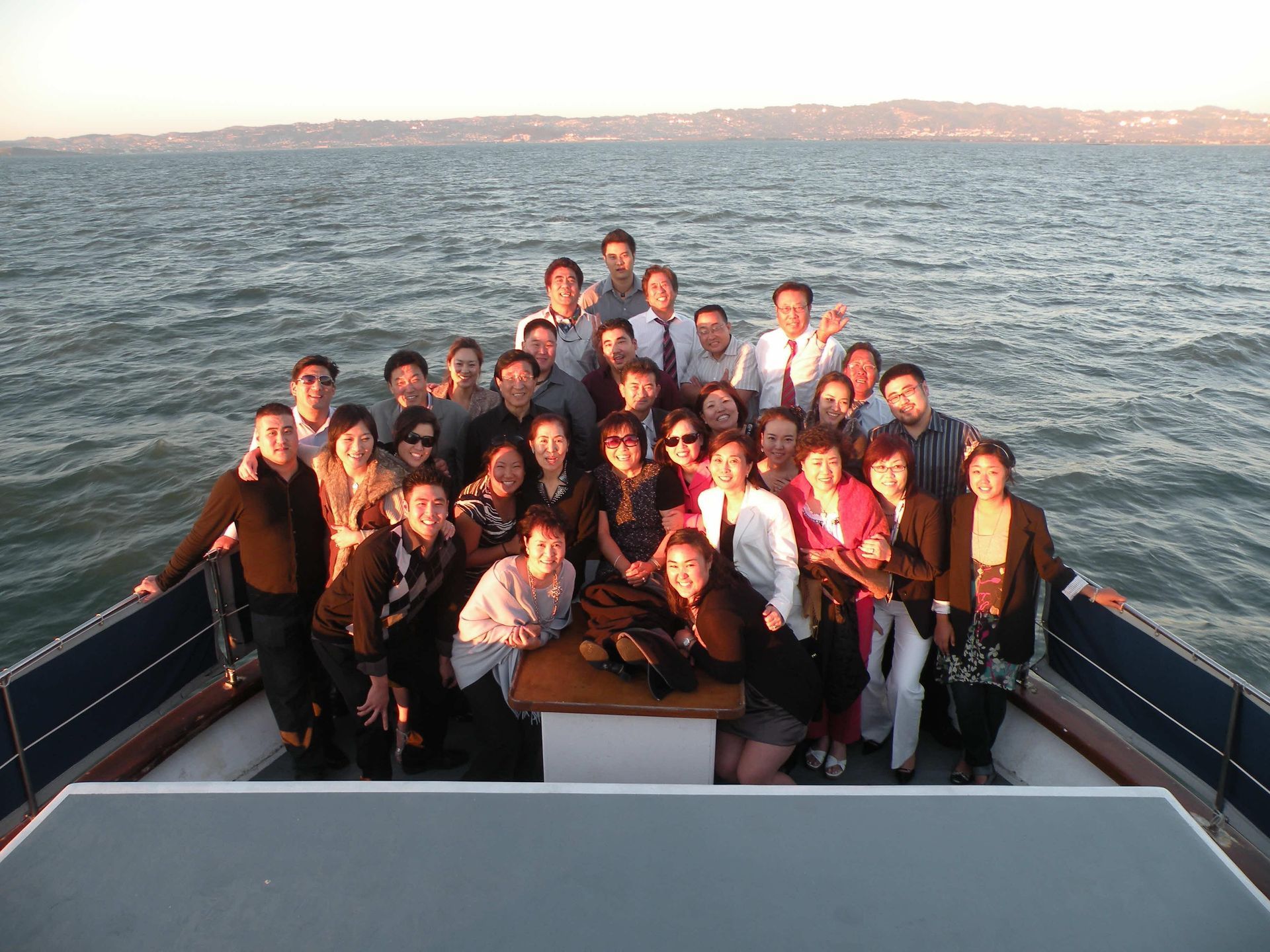 People on a boat toast with drinks against a sunset.