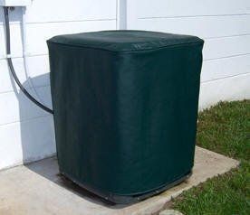 A green air conditioner is sitting on a sidewalk next to a white wall.