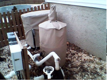 A hose with a cover on it is next to a fence