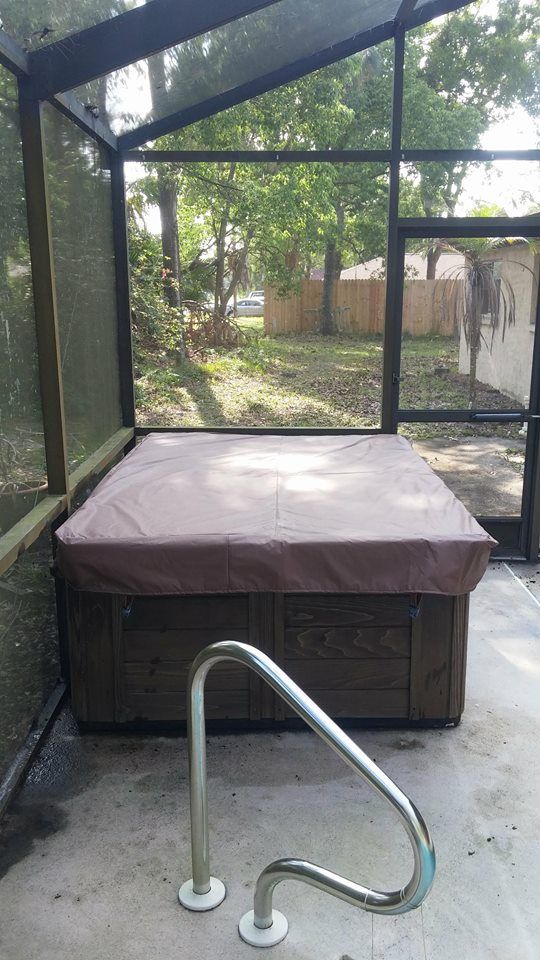 A hot tub is sitting in a screened in area next to a swimming pool.