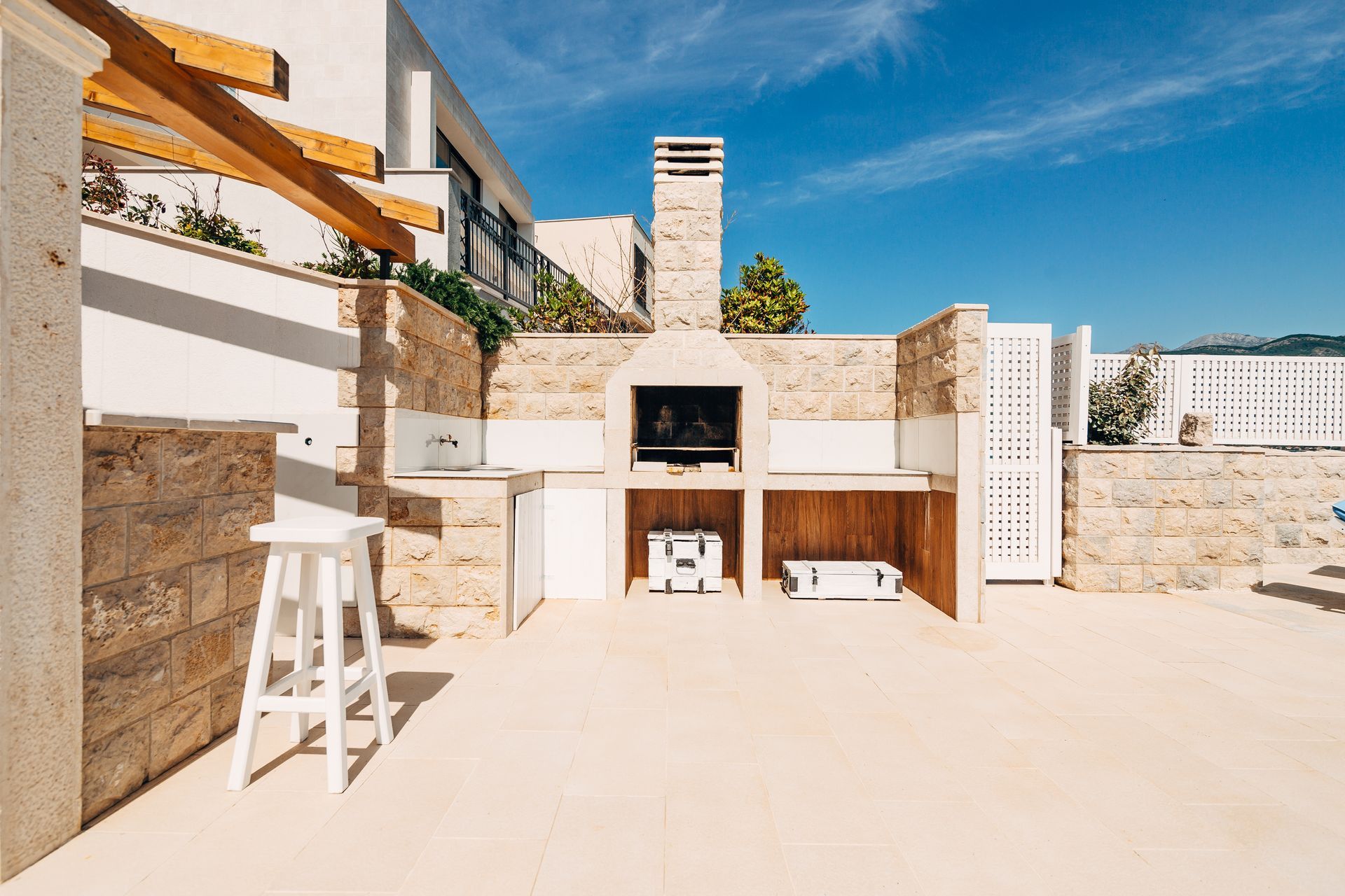 A patio with a bbq and stools on a sunny day.