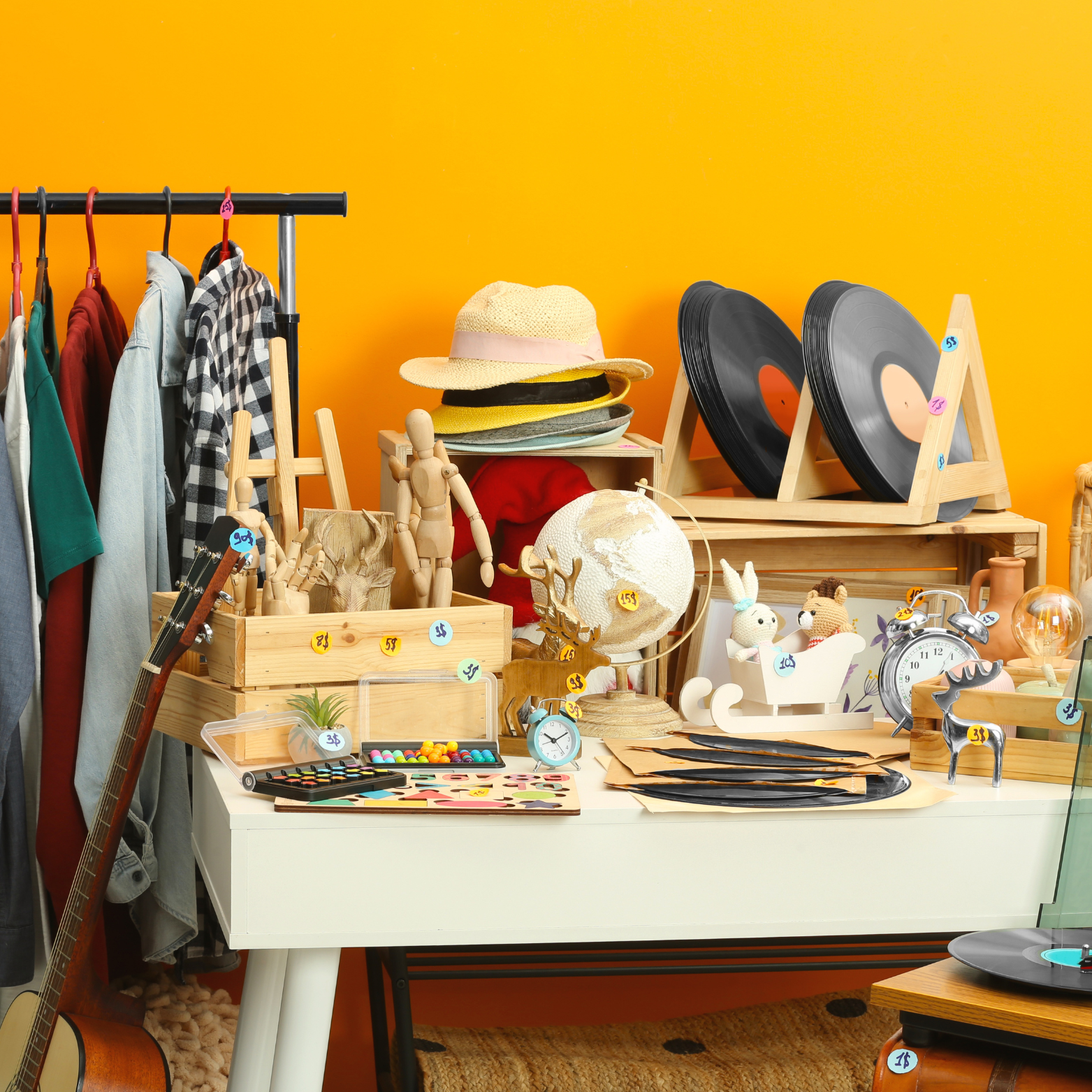 A table with a lot of items on it including hats and records