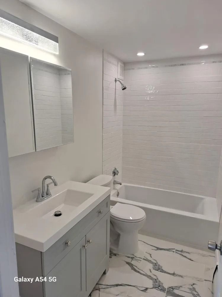 Modern white bathroom with vanity, toilet, tub, and tiled walls