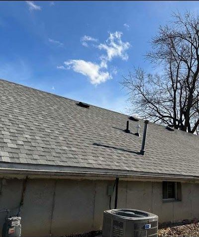 A house with a roof and a tree in the background.