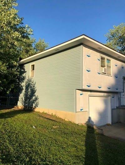 A house with a blue siding is sitting on top of a lush green lawn.