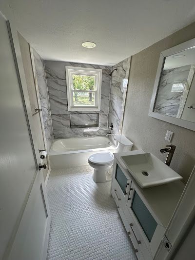 A bathroom with a sink , toilet , tub and mirror.