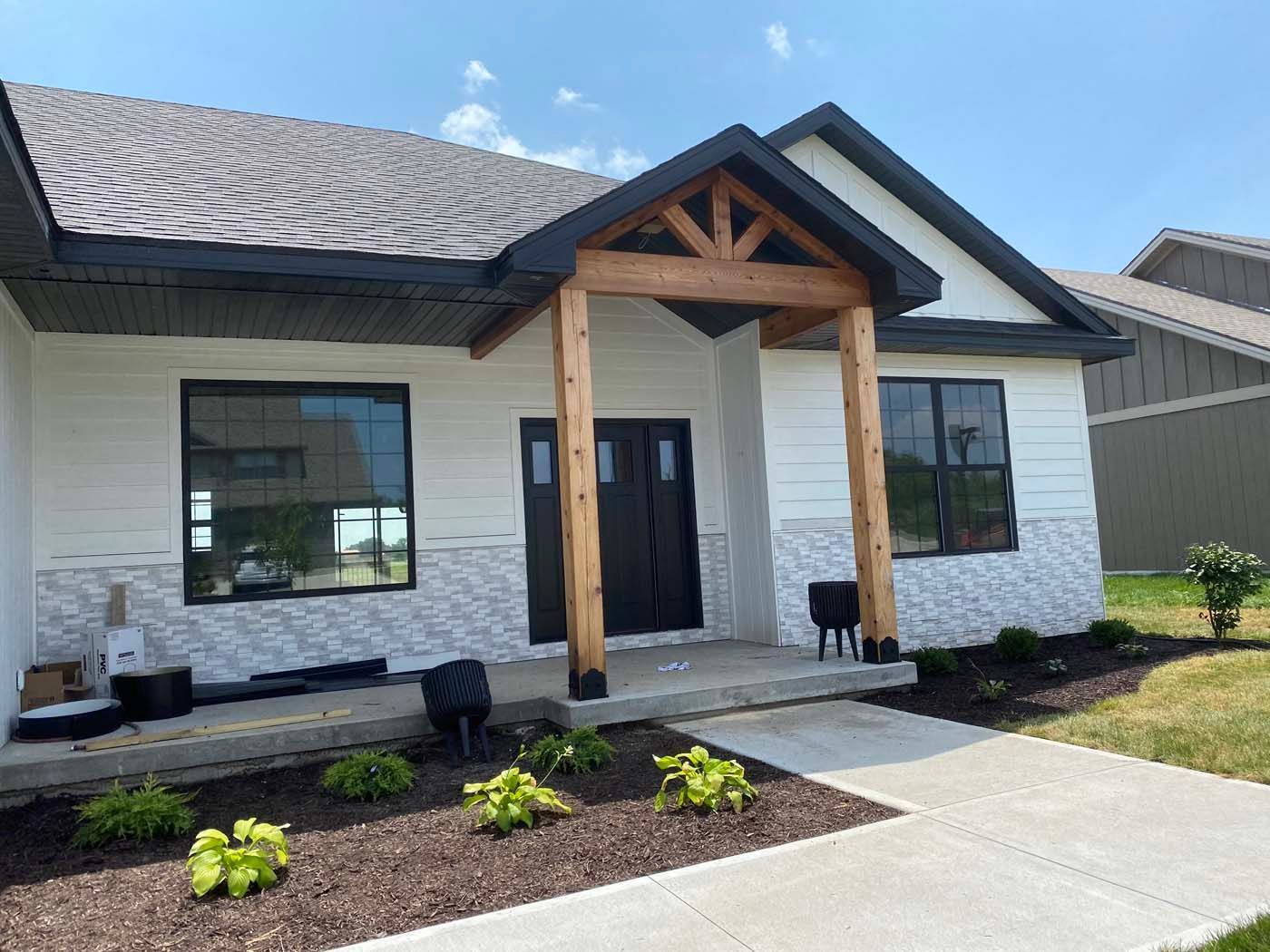 A white house with a black door and a wooden porch.