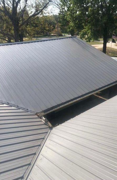 A close up of a metal roof with trees in the background.