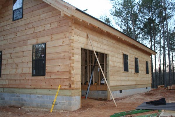 Wooden house under construction with windows and doorway.