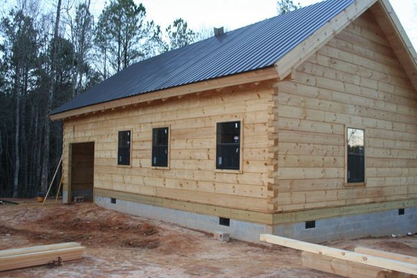 Construction of a wood-sided building with a metal roof. 