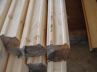 Stack of unfinished lumber with brown, angled ends.