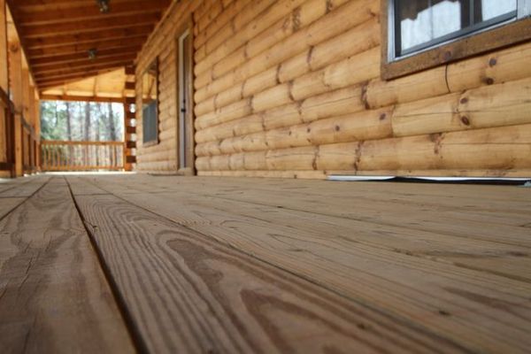 Wooden deck and log cabin exterior. Sunlight on wood.