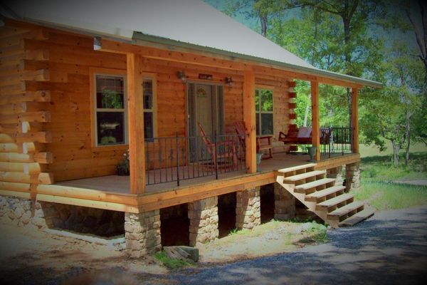 Log cabin with a porch and stone foundation.
