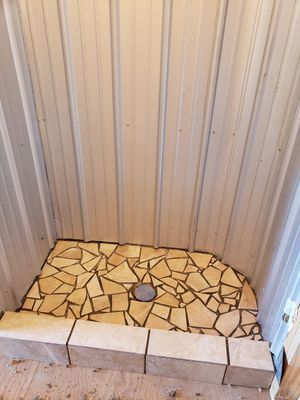 Shower stall with a tiled floor and metal walls.