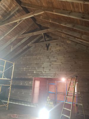 Interior view of an old wooden barn with exposed beams and scaffolding. 