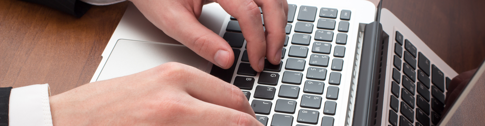 A person is typing on a laptop computer keyboard