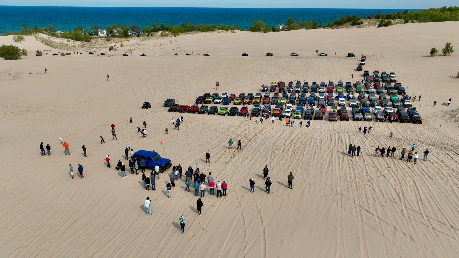 Vehicles and people gathered on a sandy beach near a shoreline.