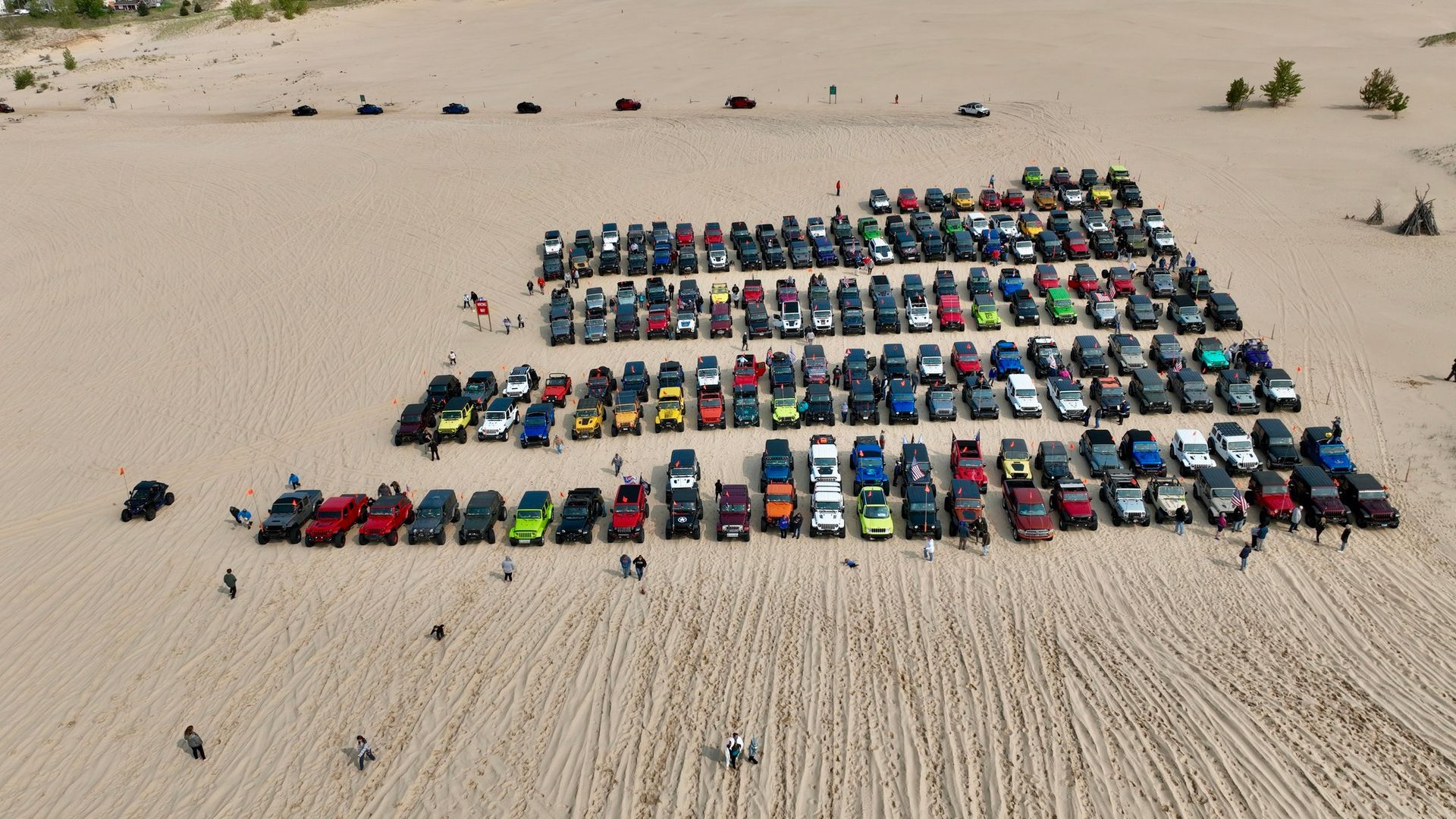 Rows of parked cars on a sand dune, likely an off-road event.