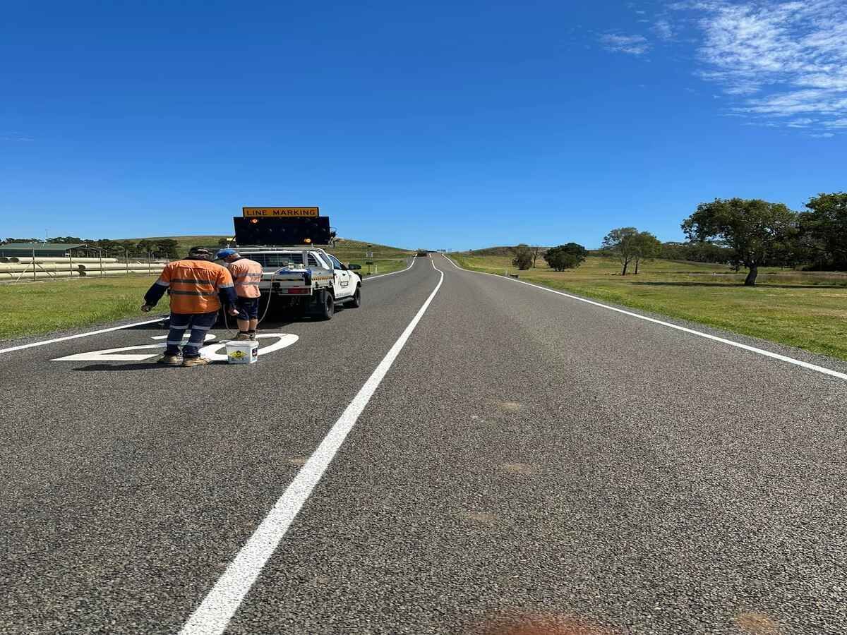 A Group Of People Are Walking Down A Road Next To A Truck — Spraywayz Linemarking Pty Ltd In Booral, QLD