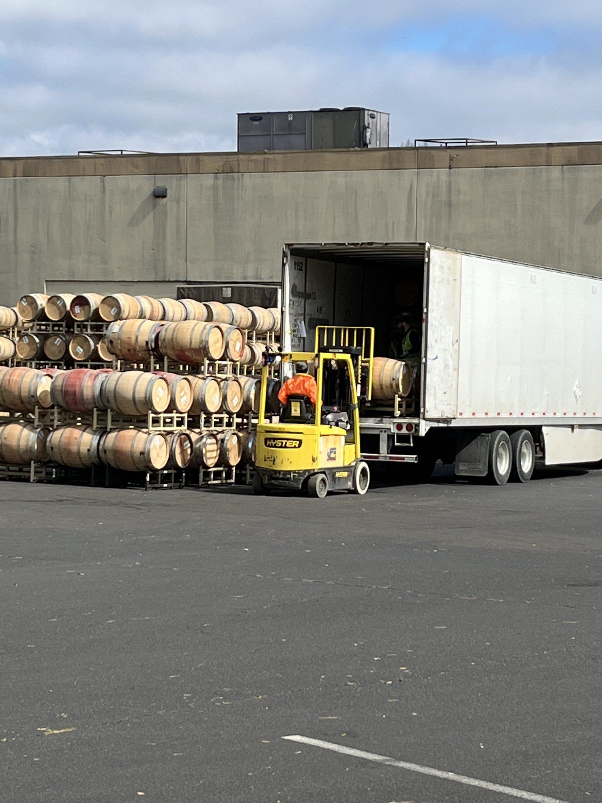 A forklift is loading barrels into a semi truck