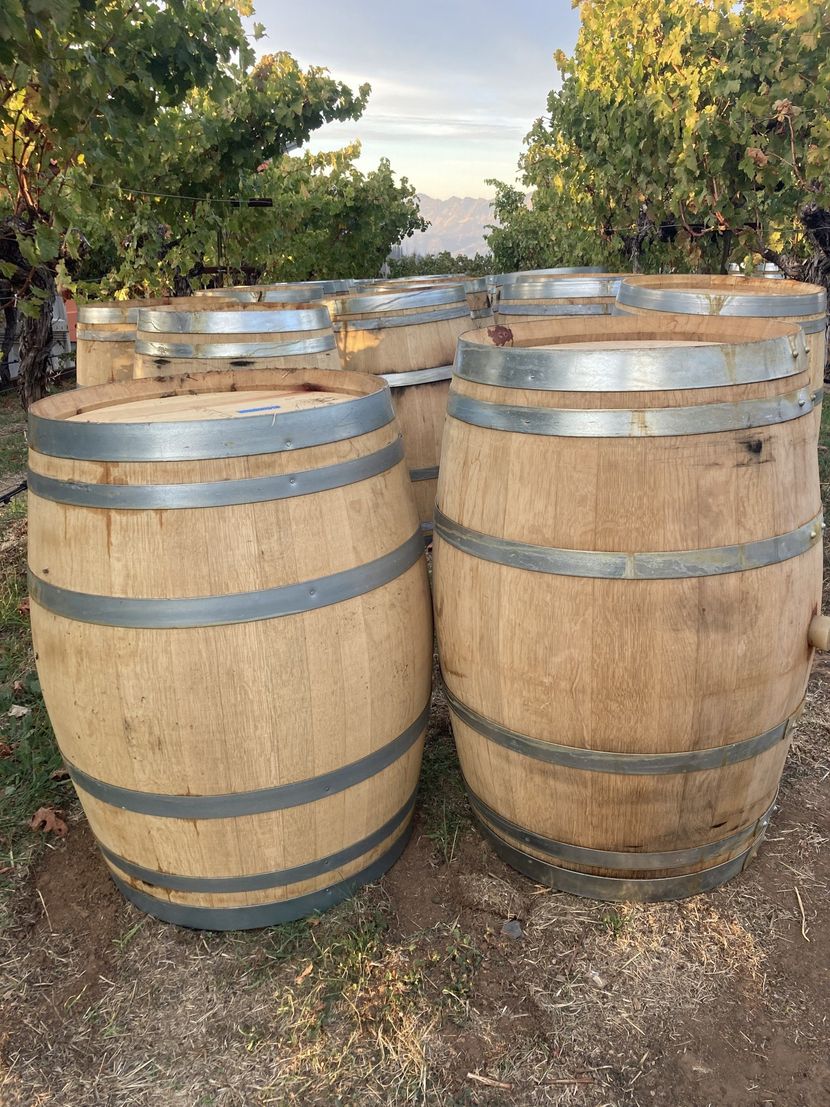 Two wooden barrels are stacked on top of each other in a field.