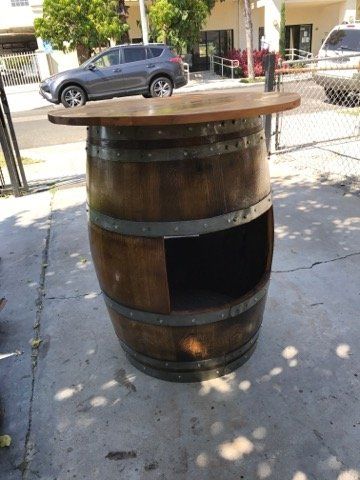 A wooden barrel with a wooden top sits on the sidewalk