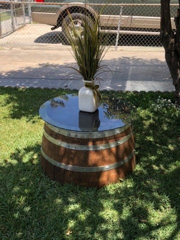 A wooden barrel with a glass top and a vase of flowers on top of it.