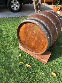 A large wooden barrel is sitting on top of a wooden stand in the grass.