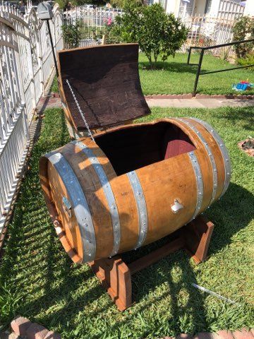 A wooden barrel with the lid open is sitting in the grass.